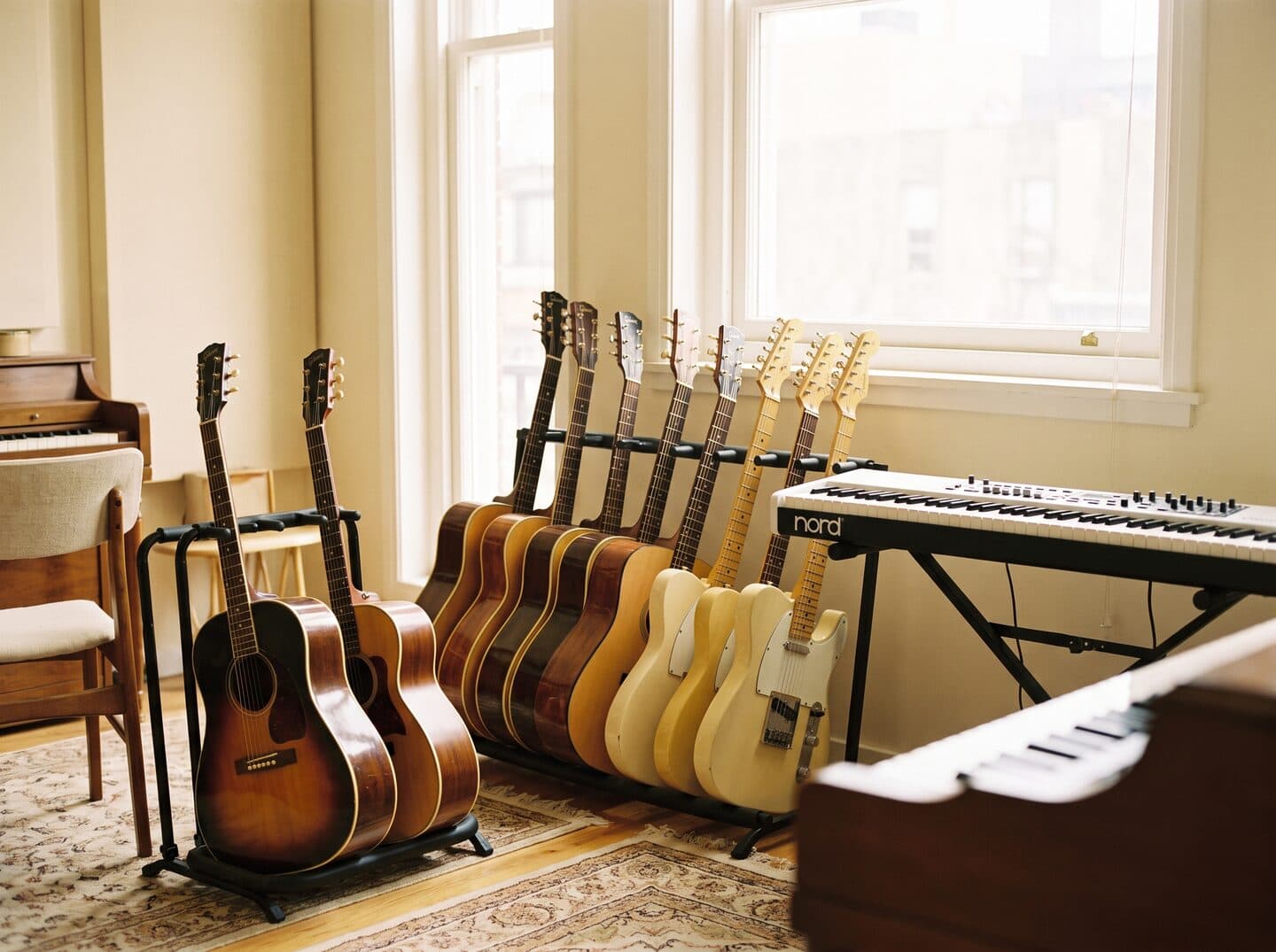 A row of guitars on a stand beside a keyboard in a bright MS Academy studio