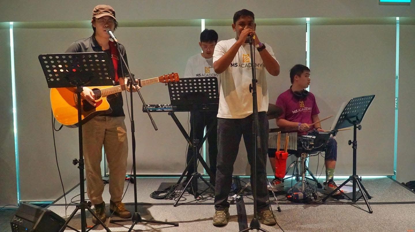 A group of learners playing guitars, keyboard and drums together in a band rehearsal