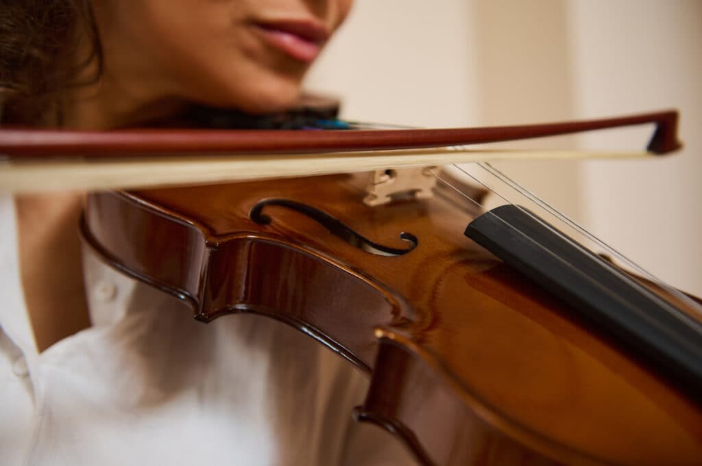 A close-up of a violinist drawing the bow across the strings